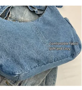 Détail macro du tissu en denim bleu délavé avec double couture blanche sur le sac hobo