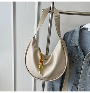 Détail du sac hobo beige avec large bandoulière en tissu et breloque corde colorée