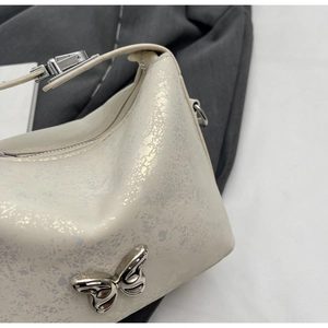Detailed macro view of cream textured bucket bag with silver butterfly metal ornament