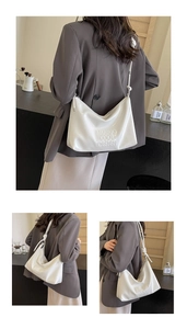 Detail view of white glossy patent leather hobo bag with embossed MUDUO text and wide strap