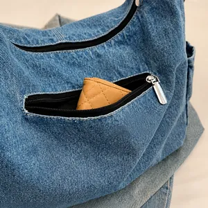 Detail van het ritsvak aan de voorkant van de denim schoudertas met opbergcapaciteit