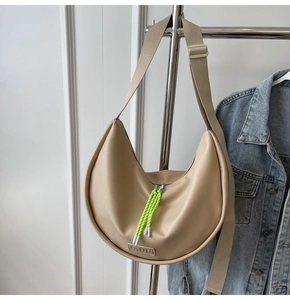 Détail du sac demi-lune beige avec tirette de fermeture néon et logo de marque embossé
