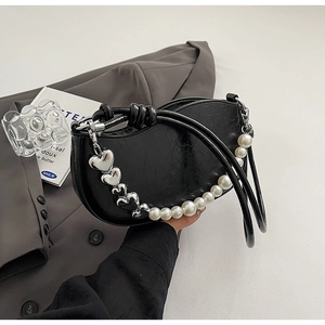 Close-up of black crescent shoulder bag featuring pearl strap and silver heart charms