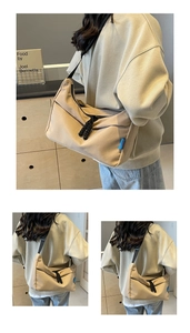 Detail of beige nylon crossbody bag featuring black woven zipper pulls and side brand label