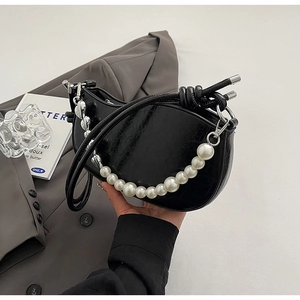Macro detail of black crescent bag featuring pearl charms and silver chain accents
