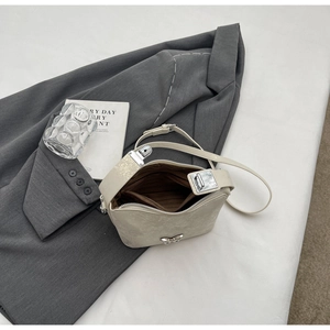 Detail view of mini off-white bucket bag featuring a silver metal bow and zip closure