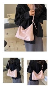 Detailed view of pink glossy patent leather hobo bag with embossed lettering design