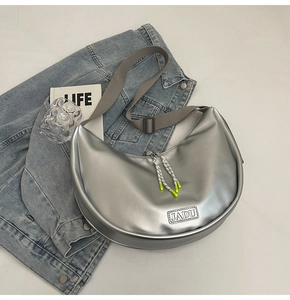 Vue détaillée du sac demi-lune argenté avec étiquette JADU sur veste en jean