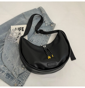 Détail du sac dumpling en cuir noir avec logo JADU et cordon de fermeture tissé