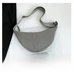 Detailed view of gray corduroy dumpling bag size compared to a smartphone