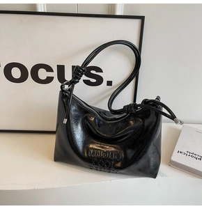 Detail of glossy black shoulder bag with knot strap and embossed Muduo Cool Design logo