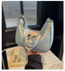 Dettaglio borsa a mezzaluna olografica argento con farfalla in metallo e texture a pieghe
