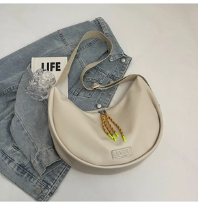 Détail du sac croissant beige avec logo JADU, tirette tressée et bandoulière en tissu