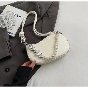 Detailed view of cream white underarm bag featuring pearl and silver heart chain decor