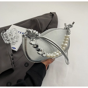 Detail of silver crescent bag featuring pearl strap and metallic heart charms