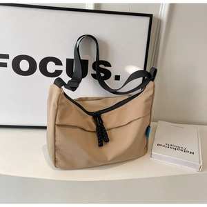 Close-up of beige dumpling bag with black zippers and durable nylon woven shoulder straps