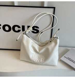 Detail of white glossy shoulder bag featuring MUDUO COOL DESIGN embossed logo and knotted strap