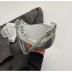 Detail of silver metallic underarm bag featuring pearl and metal heart chain handle