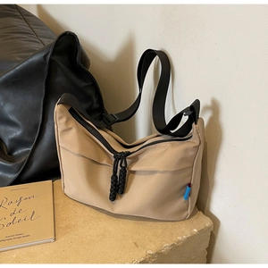 Detailed close-up of khaki nylon crescent bag featuring corded zippers and side woven label