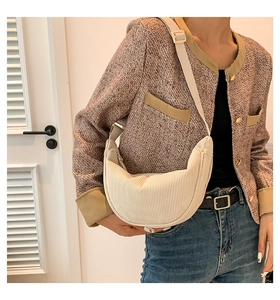 Detail of cream corduroy dumpling bag featuring soft vertical texture and adjustable strap