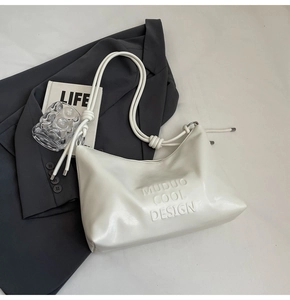 Detail of white glossy underarm bag featuring embossed lettering and tied strap design