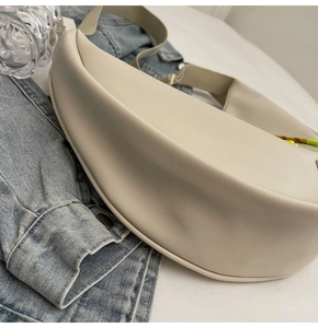 Sac à bandoulière demi-lune minimaliste en cuir crème avec une texture lisse et élégante