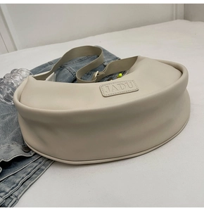 Détail du sac bandoulière demi-lune crème avec gaufrage JADU et large sangle en tissu
