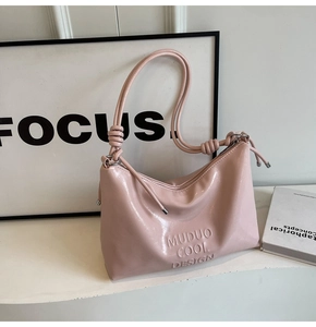Close-up of pink PU leather underarm bag featuring embossed lettering and knotted strap detail