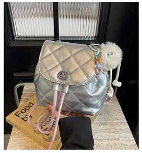 Détail du mini sac à dos argenté matelassé avec bretelles roses et breloque monstre en peluche