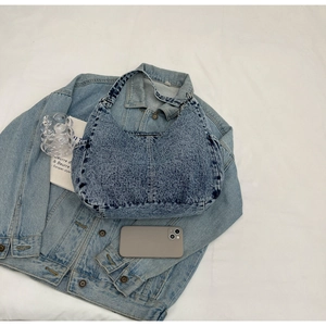 Détail d'un sac hobo rétro en denim bleu délavé avec smartphone pour comparer la taille