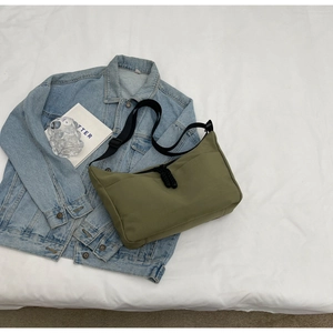 Detailed overhead view of green nylon dumpling bag on denim jacket with casual accessories