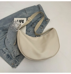 Gros plan du sac demi-lune crème avec texture lisse et large bandoulière réglable