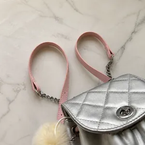 Detalle del bolso acolchado plateado con correa de cadena rosa y cierre de metal liso