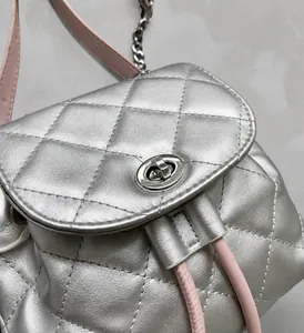 Detalle del bolso acolchado plateado con cierre giratorio de metal y cordón rosa