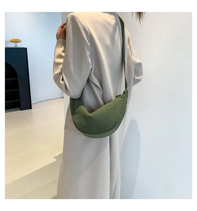 Detail of fruit green corduroy dumpling bag worn on shoulder with cream blazer