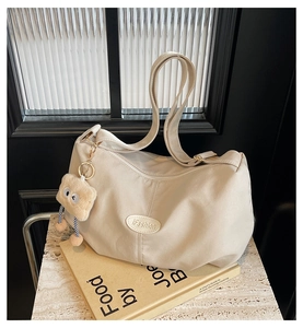 Detailed macro view of beige pleated tote bag with plush charm on marble surface