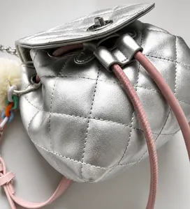 Detalle de mochila plateada acolchada con cierre de giro y cordón rosa