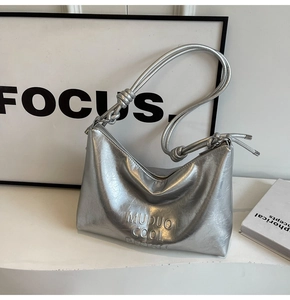 Close-up of metallic silver shoulder bag with crinkled texture and unique knotted strap