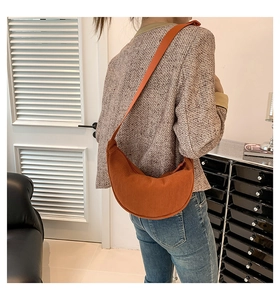 Detail of caramel corduroy crescent bag shown on model in a minimalist indoor setting