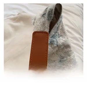 Detail of embroidered floral tote with fringe texture and premium brown leather handle