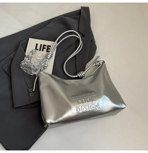 Detail of silver metallic tote bag with distressed texture and knotted shoulder strap