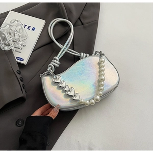 Detail of silver metallic pearl handbag with heart chain next to a blazer and magazine