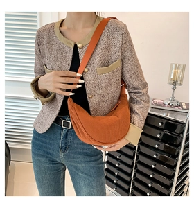Close-up of orange pleated crescent bag showing the textured fabric and crossbody strap