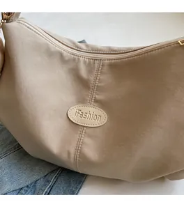 Detail of beige pleated shoulder bag with iFashion embossed logo and gold zipper