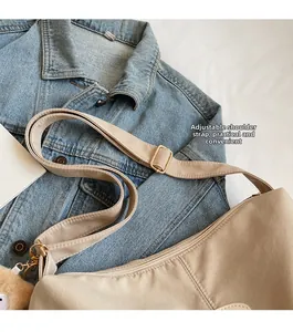 Adjustable shoulder strap of beige nylon tote bag with golden metal buckle and bear charm