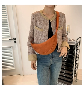 Lifestyle shot of an orange corduroy crescent crossbody bag with an adjustable strap
