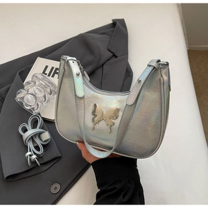 Dettaglio della borsa a mezzaluna olografica argento con fibbia a farfalla su blazer grigio