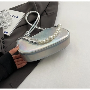 Detail of silver iridescent baguette bag with pearl and heart chain on suit background