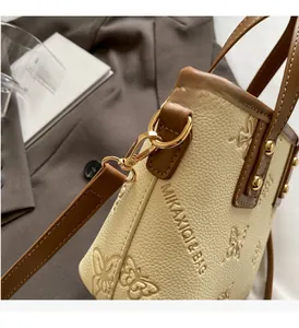 Detailed view of cream leather bucket bag with butterfly embossing and gold hardware