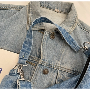 Détails de la texture denim bleu clair et mousquetons en métal argenté sur le sac à main